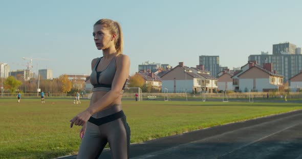 Athletic Blonde Woman Finishing Running and Bending Over To Catch Her Breath alt