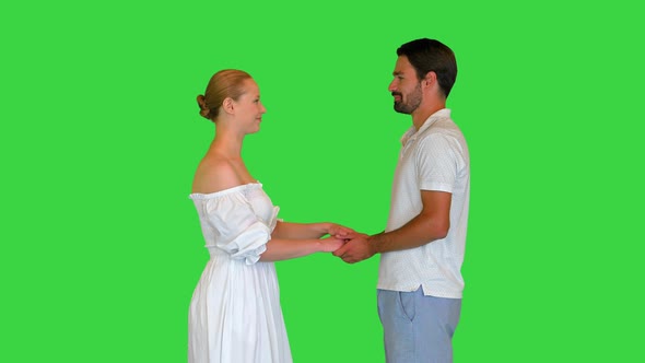 Young Couple in Love Holding Hands Looking at Each Other on a Green Screen Chroma Key alt