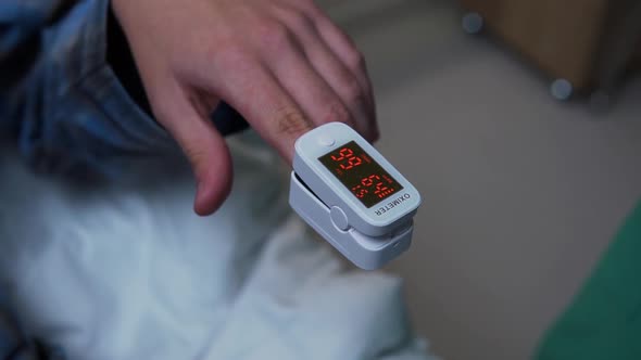 Doctor attaches pulse ox on finger of patient lying on bed