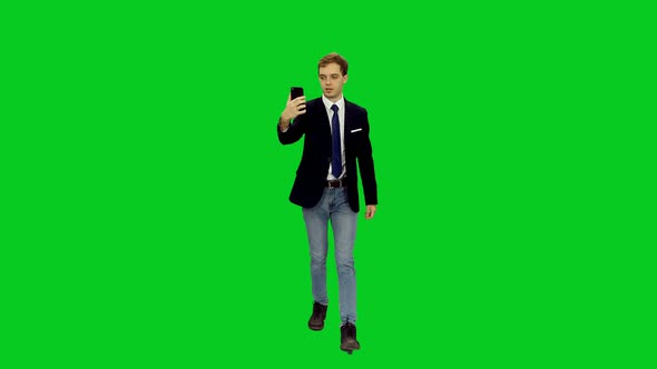 Young Businessman Talking Via Mobile Phone Video Camera while Walking on Green Screen