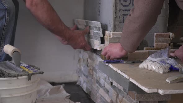 Male Hands Setting Stacked Stone Tiles for a Fireplace alt