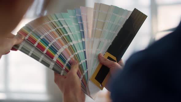 Unknown Couple Choosing Color for Walls on Swatches Book on Blurred Background alt