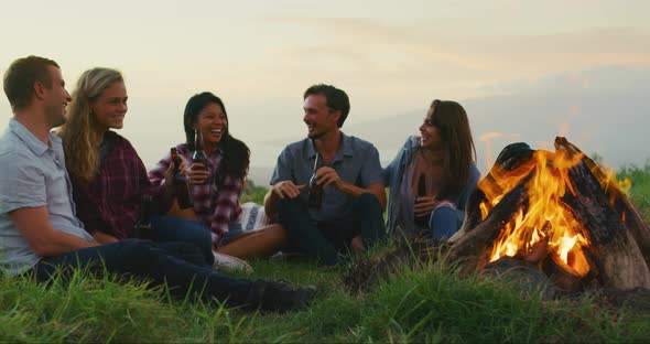 Friends Relaxing at Sunset Campfire alt