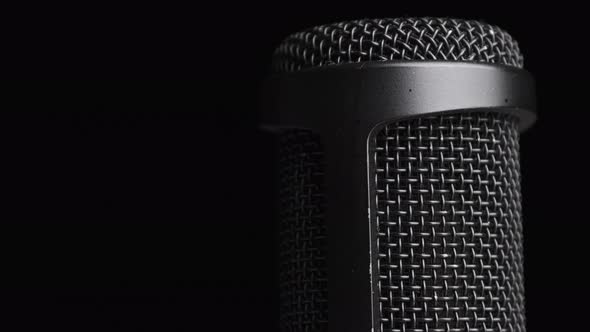 Studio Condenser Microphone Rotates on Black Background with Place for Text alt