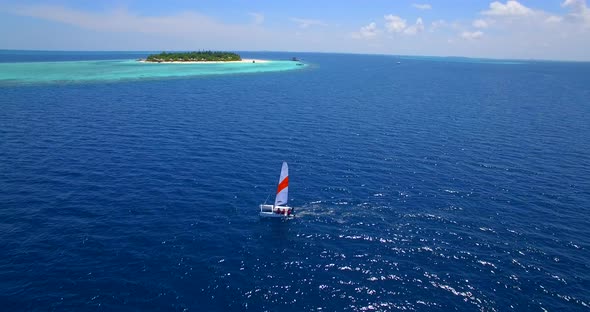 Aerial drone view of a man and woman sailing on a boat to a tropical island alt