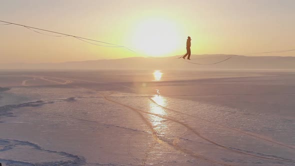 The Tightrope Walker Is Balancing on a Rope Between Two Rocks Above a Frozen Lake