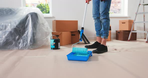 Caucasian Man Prepares for Repairs in New Apartment and Puts Roller in Container with Green alt