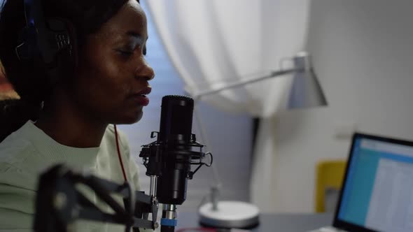 Close Up of African Blogger Woman Speaking at Microphone During Podcast alt