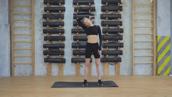 Attractive fit sporty woman doing exercises on mat in bright room fitness training at gym alt