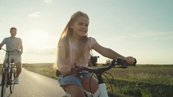 Family of four caucasian people riding bikes on village road. Shot with RED helium camera in 8K. alt