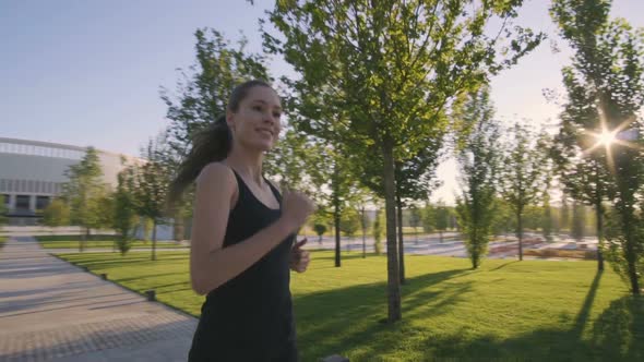 Sports Woman Makes Morning Jog and Physical Exercises In  Park alt