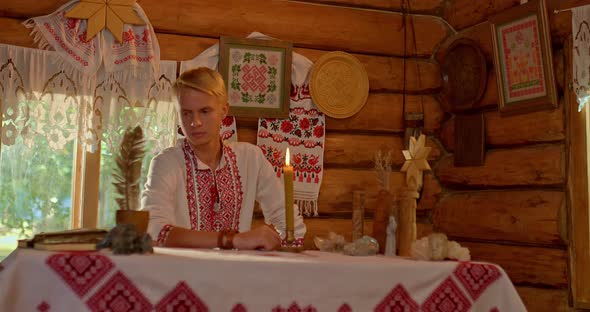 Portrait a Man in a Folk Costume Sits at a Table in a Russian Hut alt