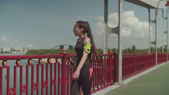 Sporty Female Jogging and Doing Push Ups on Bridge alt