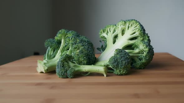 Bright and Fresh, Slow Push-in to Sliced Raw Broccoli on Light Wooden Tabletop alt