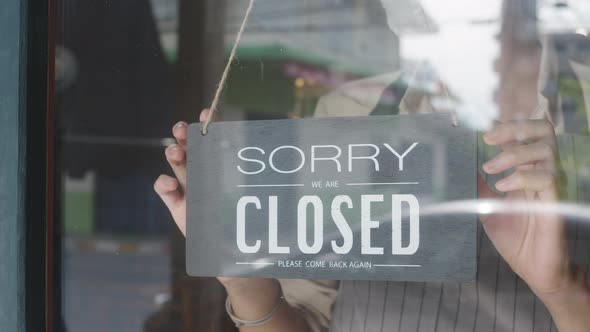 Young Asia girl wear face mask turning a sign from open to closed sign. alt
