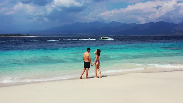 Young man and woman married on vacation live the dream on beach on sunny white sandy 4K background alt
