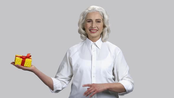 Happy Old Lady Holding Gift Box on Her Palm alt
