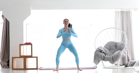 Young athletes woman in sportswear doing squat at home. alt