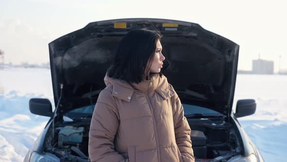 Upset Woman Shrugs Standing Near Broken Automobile in Field alt