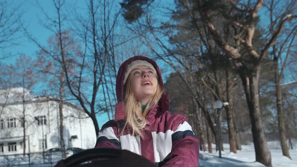 A Young Mother Walks with Her Child in a Stroller on a Clear Winter Day alt