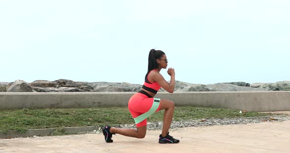 Beautiful fitness young black woman in sporty tight using rubber band resistance.