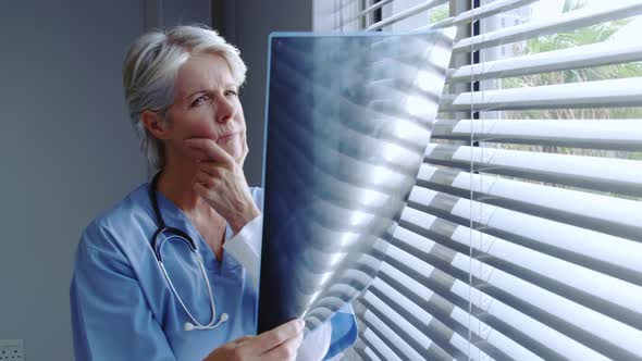 Front view of mature Caucasian female doctor looking at x-ray report in hospital alt