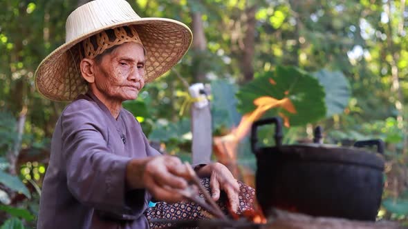 An old woman lighting a cooking fire