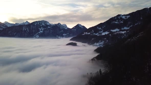 Flying far over the fog. A small hill is looking out of the fog. alt