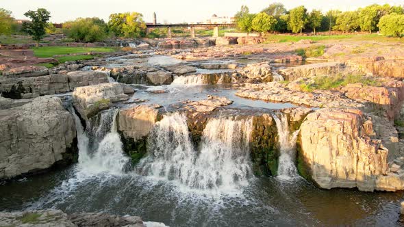 Falls Park waterfall on a bright sunny day. Water flowing over several levels of rocks.