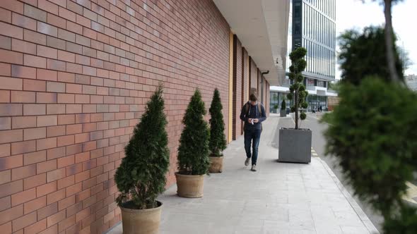 Caucasian Young Man with a Guitar on the Back Is Putting on a Medicinal Mask alt