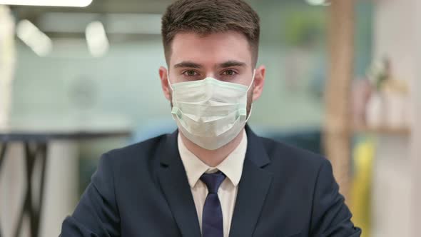 Young Businessman with Face Mask Looking at the Camera alt
