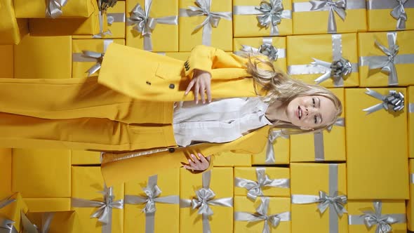 A Pretty Young Blonde Dressed in a Yellow Suit Poses in Front of the Camera Against the Background