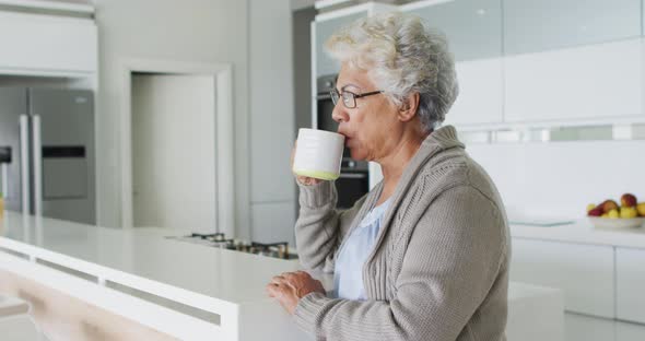 African american senior woman drinking coffee in the kitchen at home alt