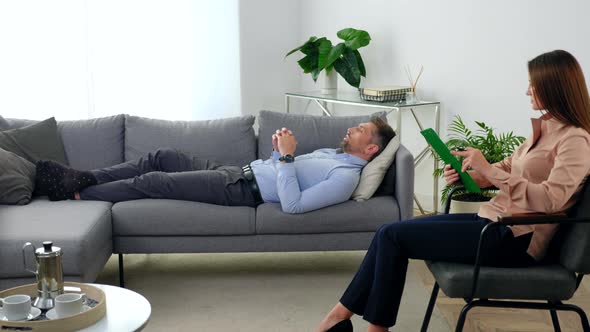 Woman Psychologist Sitting on Chair Listens Patient at Psychotherapy Session alt