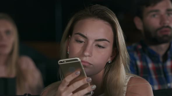 Shot of a Beautiful Young Female Texting During Movies at the Local Cinema alt