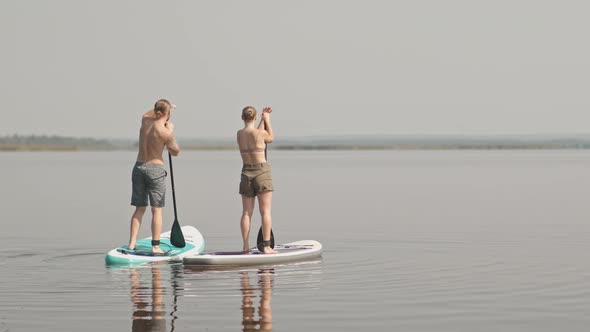 Couple Stand Up Paddling on Sup Boards in Lake alt