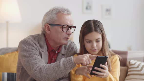 Caucasian Grandfather Teaching Girl How to Use Smartphone alt