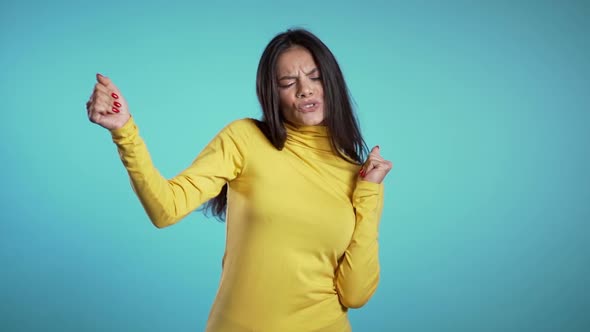 Funny hispanic woman having fun, smiling, dancing in studio against blue background alt
