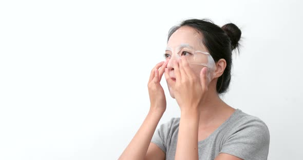 Woman applying paper sheet mask on face alt