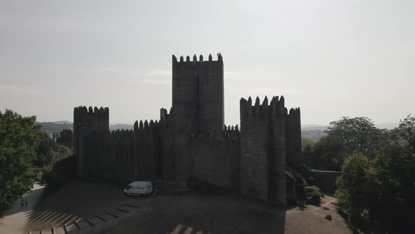 Ascending Flyover Historic Stone Castle silhouette on bright light, Guimarães, Portugal