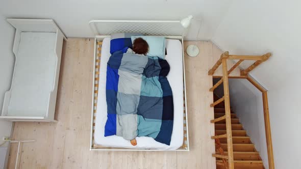 a Top Aerial View of a Person Who is Tossing and Turning in Bed Under a Blanket Trying to Fall alt