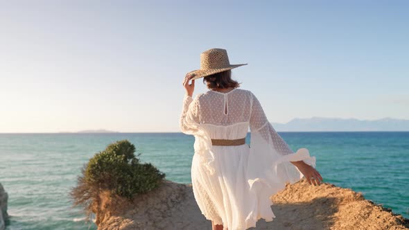 Young Fashionista Woman on Cliff Over Ocean with Teal Water alt