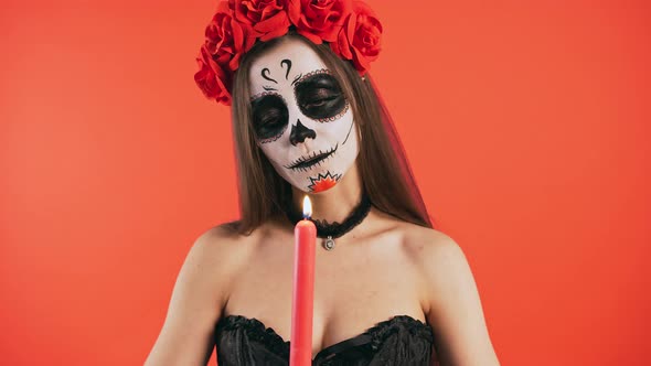 Day of Dead Female with Skull Makeup Holding Burning Candle Looking at It and Extinguishing Posing alt