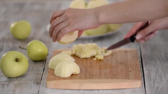 Young Woman's Hands Cutting an Apple on Wooden Cut Board alt