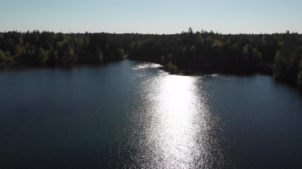 Sun Reflection On Lake Reveal Island Botrsl Forest Backwards Aerial alt