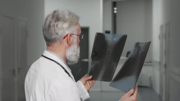 Senior Doctor Smiling To the Camera While Examining Xray Scans