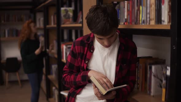 Young Handsome Man Standing Leaning on Reading a Book  Commuter Student Knowledge Concept alt
