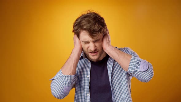 Young Man Suffering From Headache Touching Head Yellow Background alt