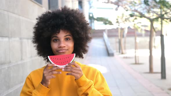 one happy and beauty cheerful woman holding a small watermelon covering her mouth.