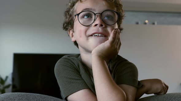 Cute kid with glasses resting on his sofa at home